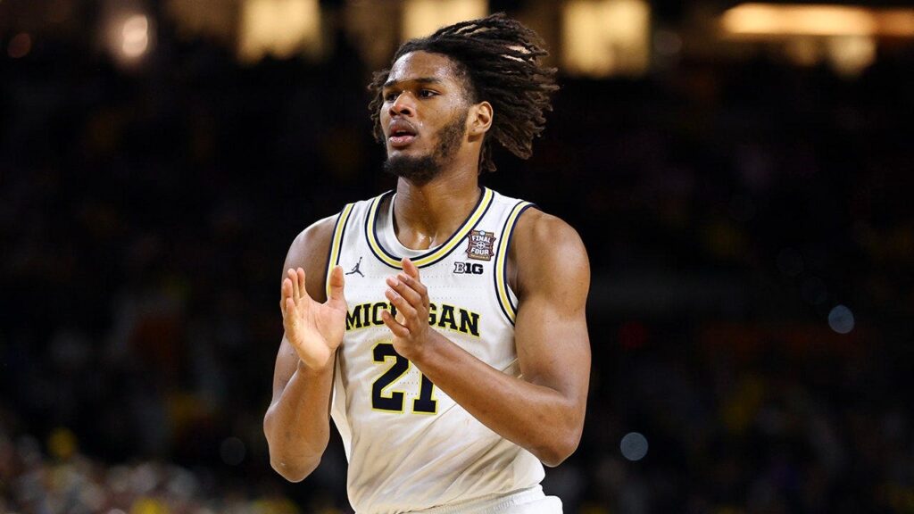 Basketball player in a Michigan jersey #21 clapping on the court during a game.